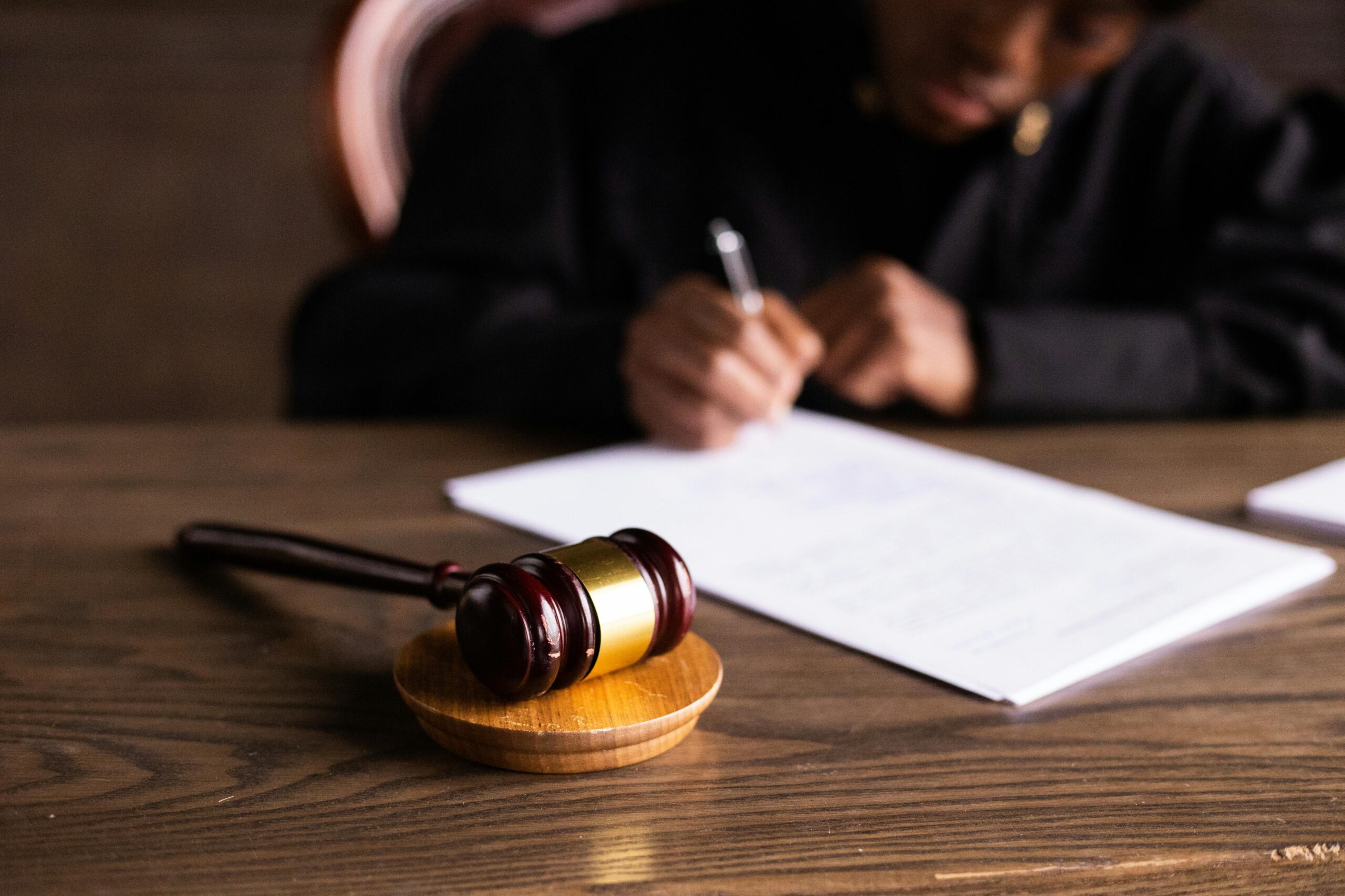 gavel on a desk with a person writing on paper in the background